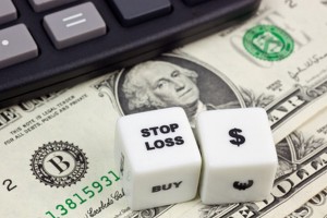 US currency with calculator and dice showing STOP LOSS